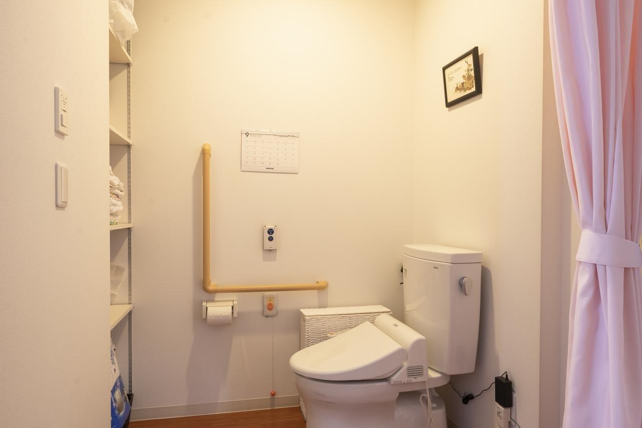 介護対応のトイレ室。手すり、温便座、呼び出しボタン完備の安全設計