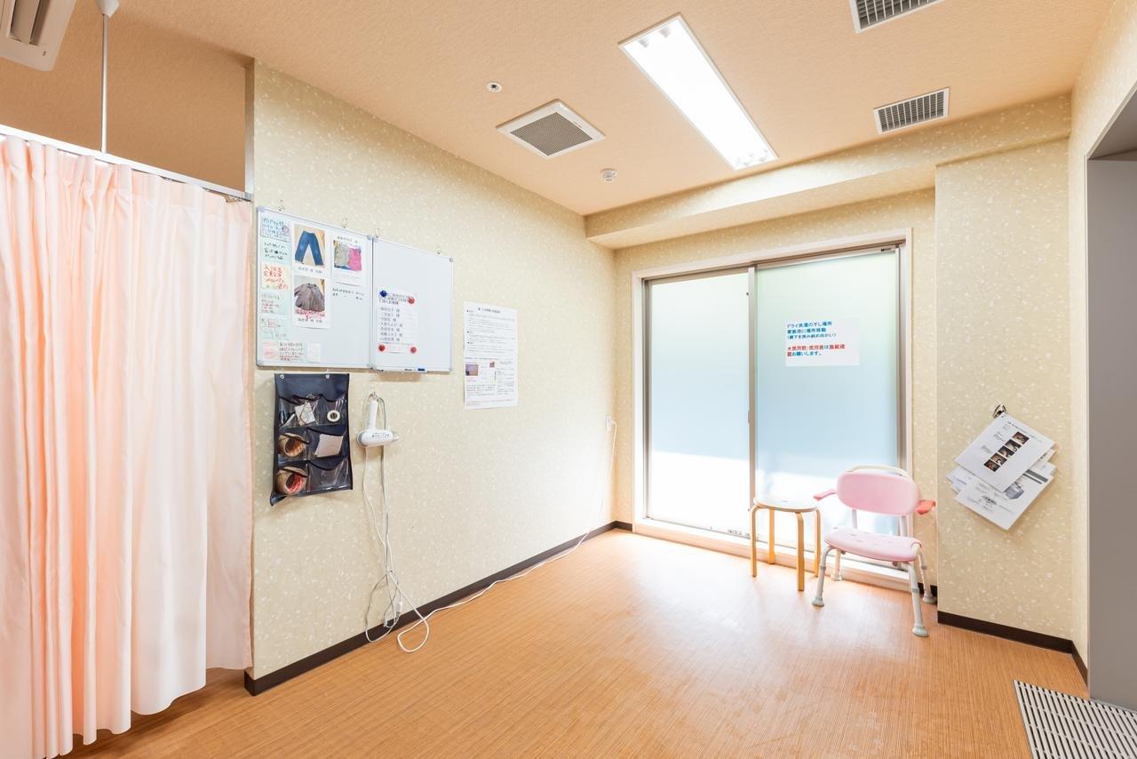 機能訓練室。ピンク色の椅子と訓練用機器が配置された明るい共用スペース。