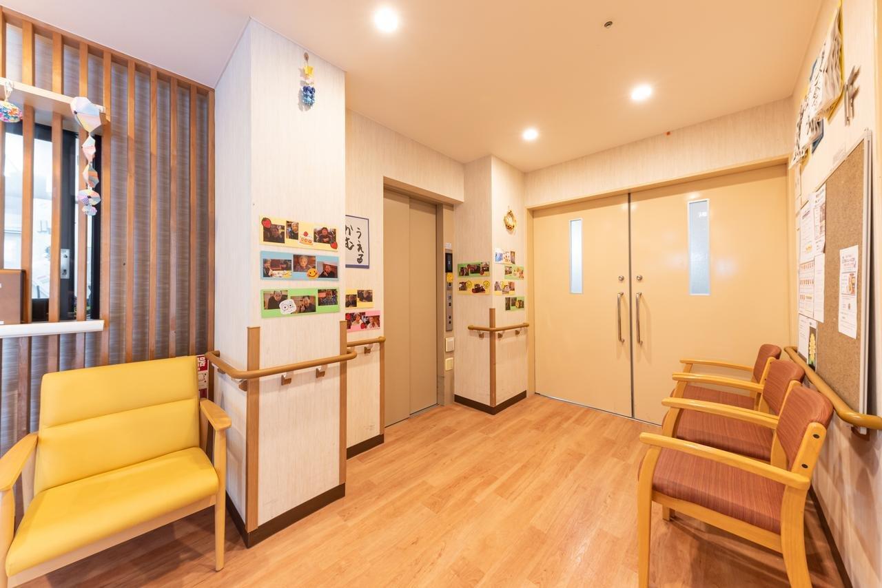 温かみのある色調のロビー・待合室。木製家具と掲示板で居心地よい空間